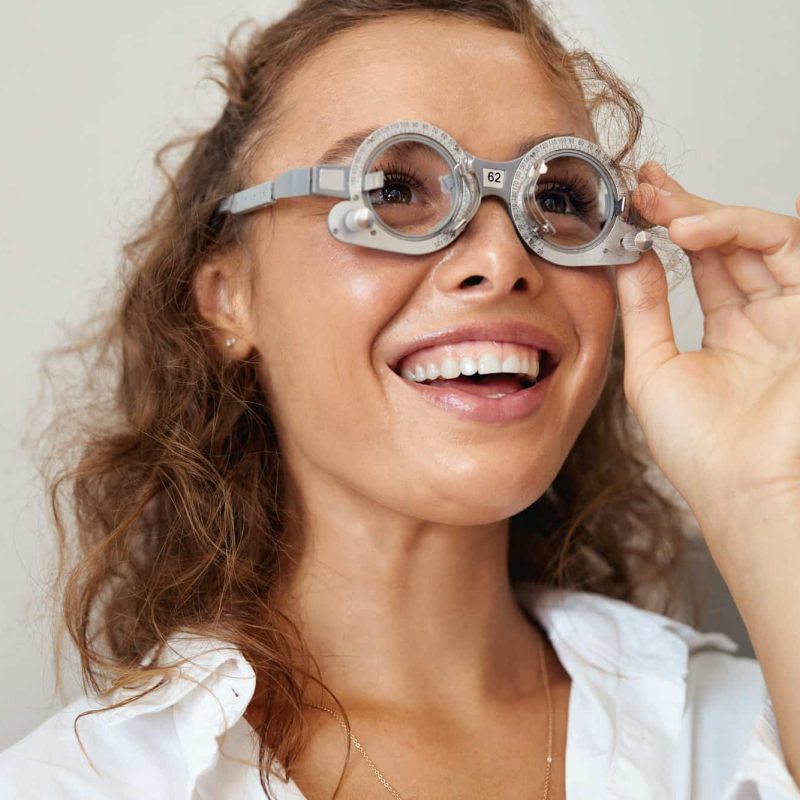 Eyesight Test. Cheerful Girl In Optometrist Trial Frame Smiling