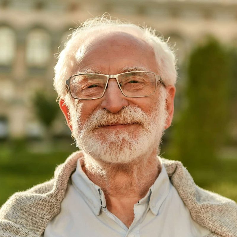 Positive attitude. Portrait of handsome bearded senior man in glasses looking at camera and smiling